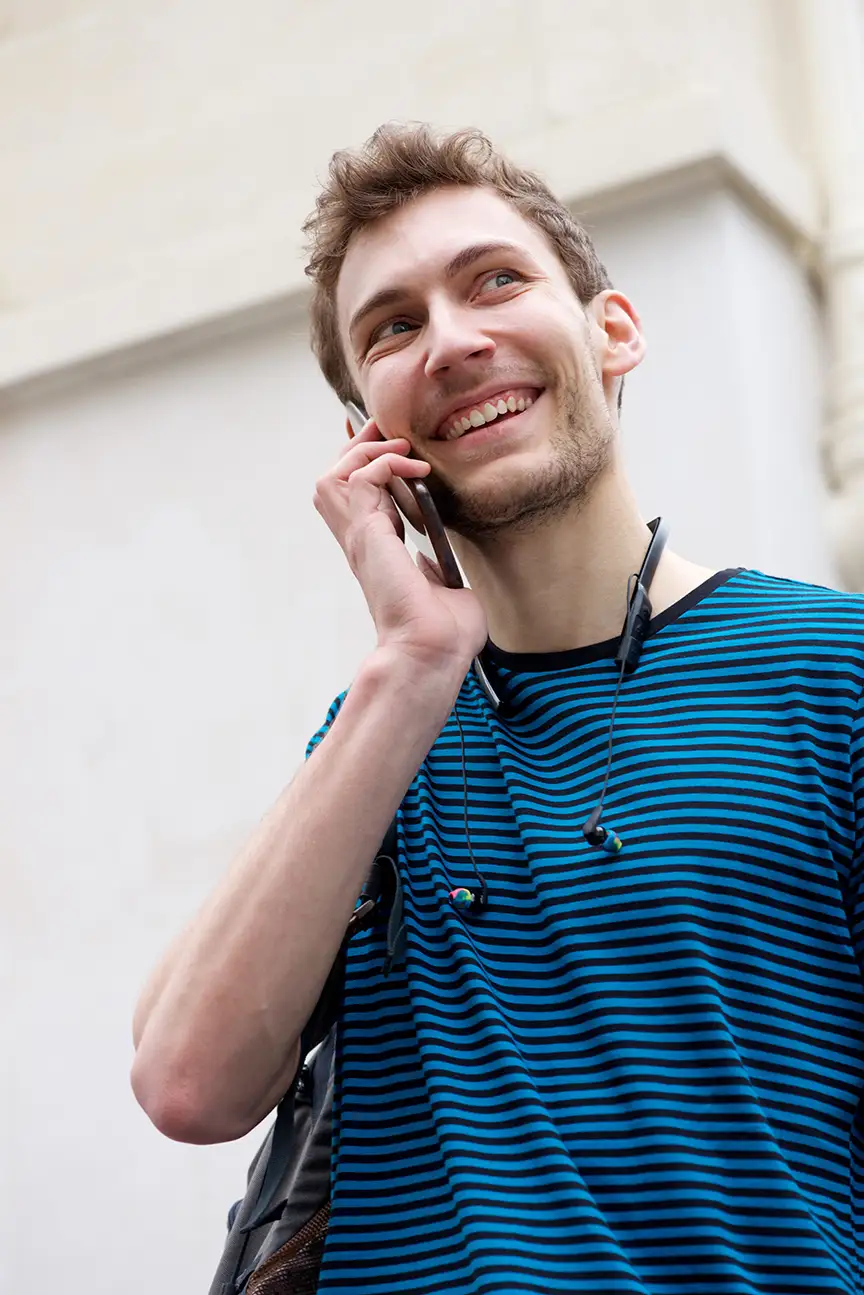 Smiling man talking on a cell phone outdoors